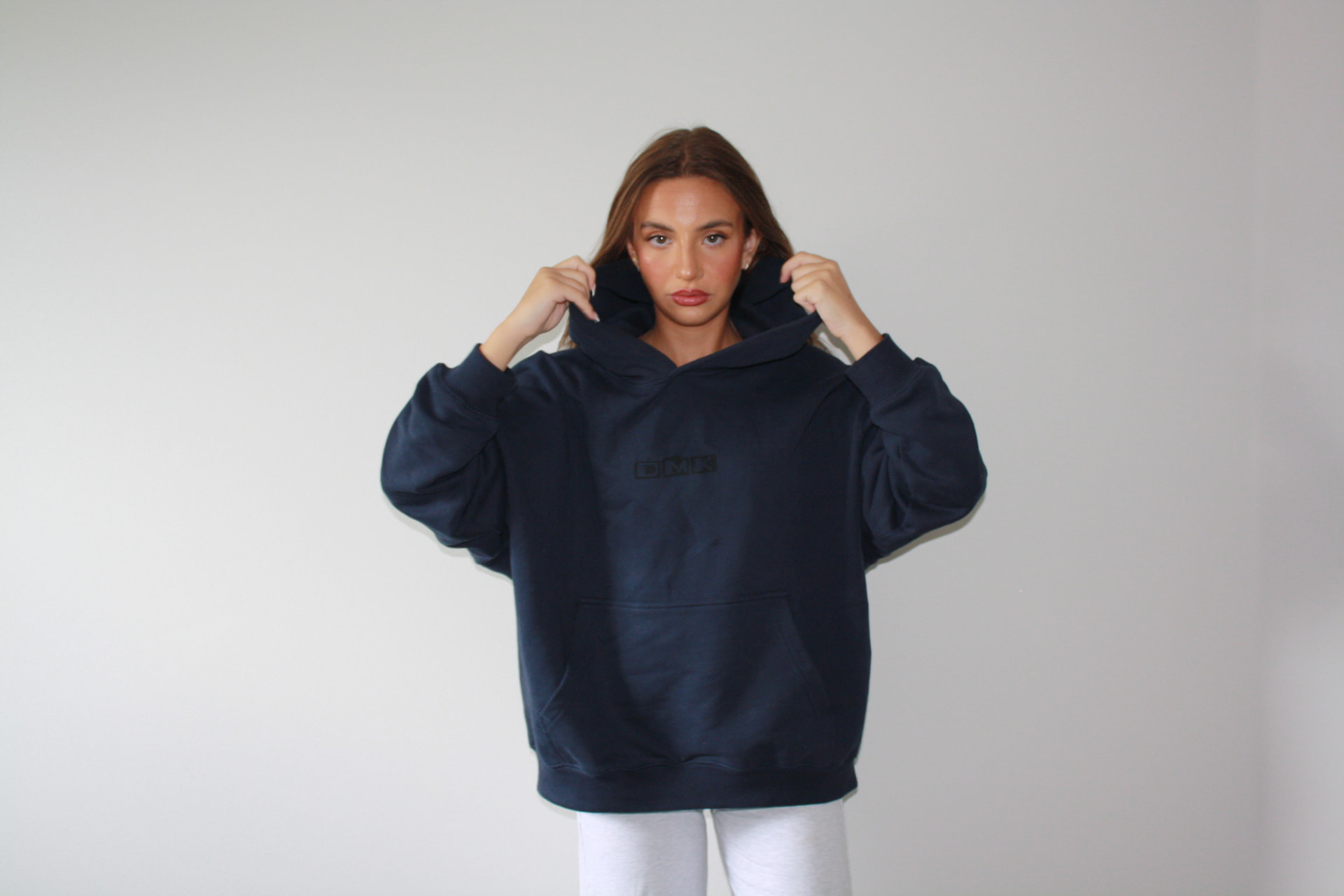 Model wearing a navy DMK Studios Premium Hoodie with the DMK logo