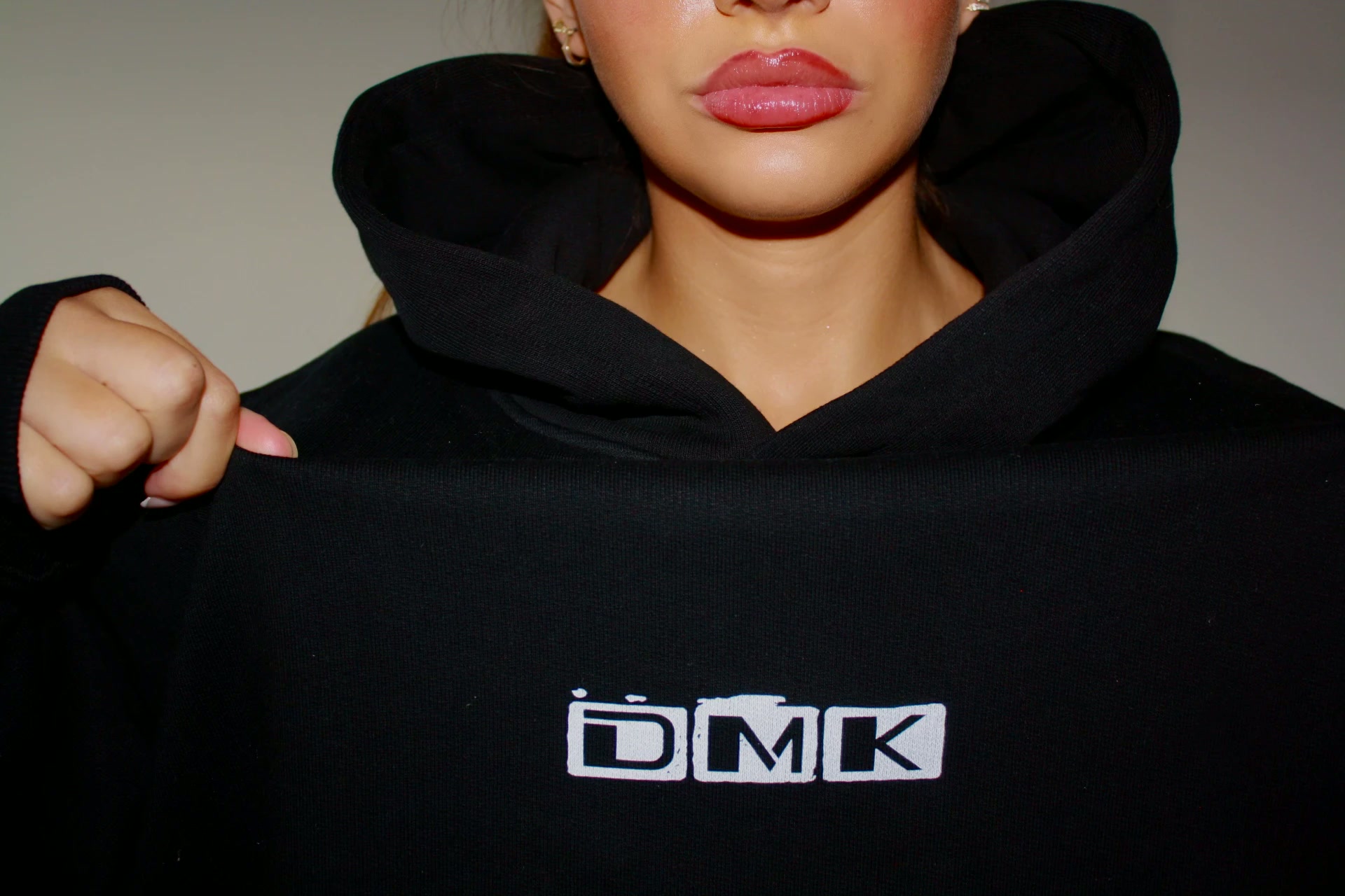 Model wearing a black DMK Studios hoodie with the DMK logo